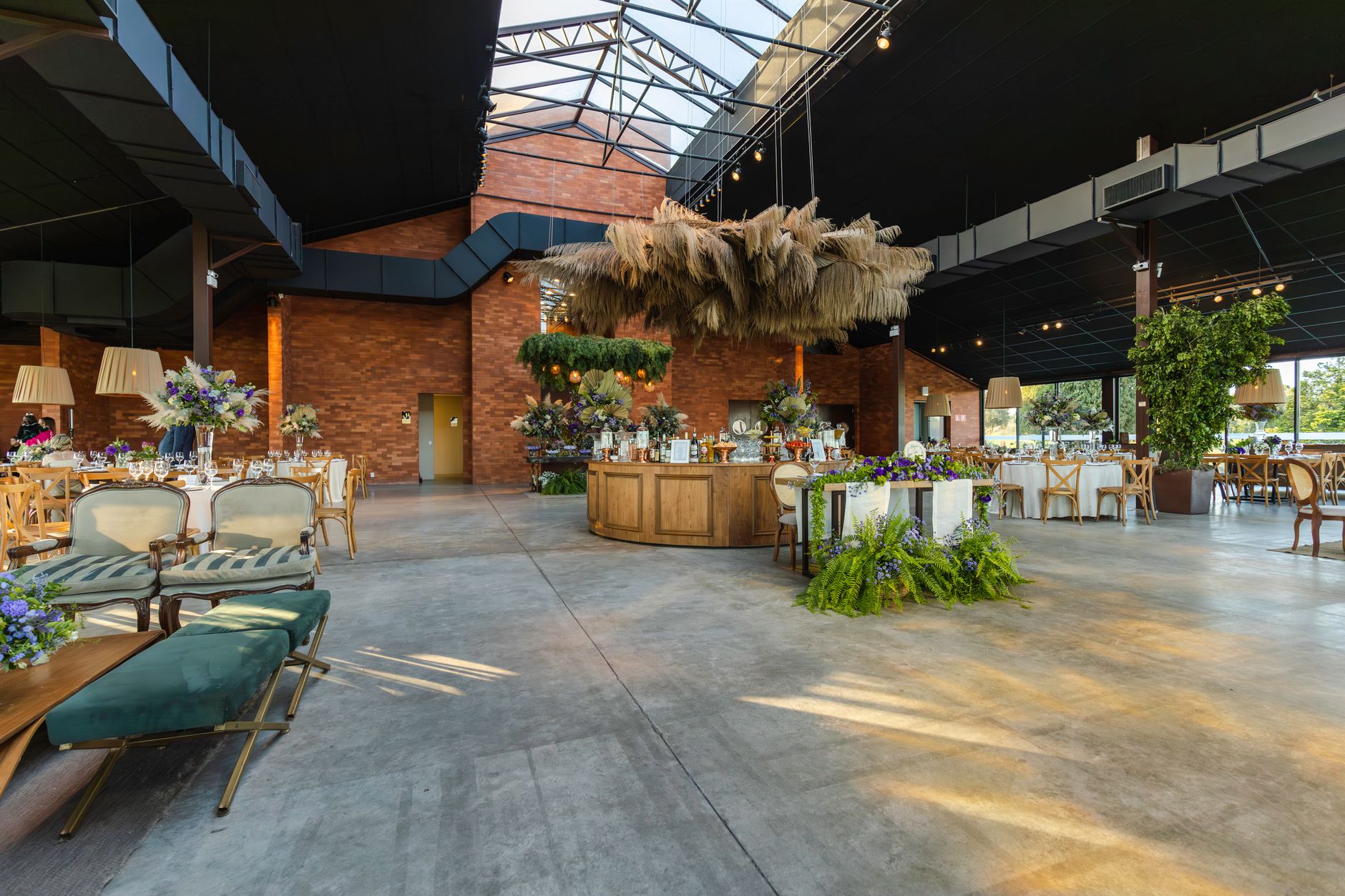 Spacious wedding venue with elegant floral arrangements and rustic decor under a modern industrial roof.