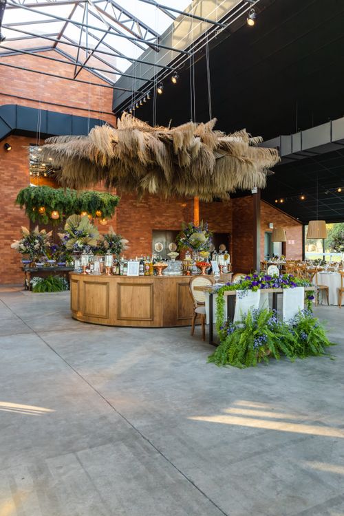 Free Spacious indoor banquet hall showcasing rustic decor with wooden furniture and green floral arrangements. Stock Photo