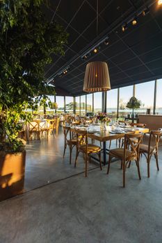 Cozy restaurant setting with elegant decor, wooden furniture, and large windows.