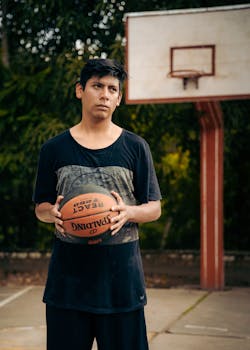 Teenage boy holding a basketball on an outdoor court in San Martín, Perú.