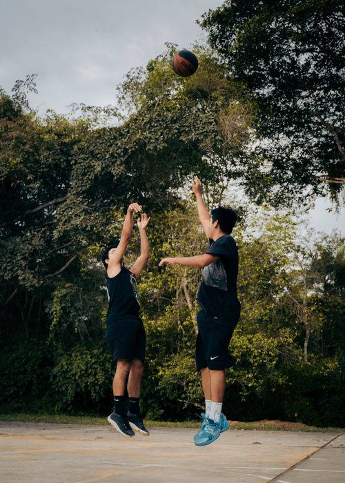 Free Two men engaging in a basketball game outdoors under natural light. Stock Photo
