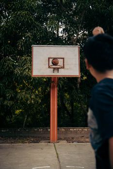 A man playing basketball outdoors in Rioja, Peru with a focused shot at the hoop.