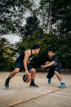 Two men playing basketball in an outdoor court surrounded by lush greenery in Rioja, Peru.