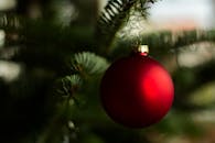 一个红色的圣诞装饰品特写镜头，挂在树枝上，是完美的节日装饰主题