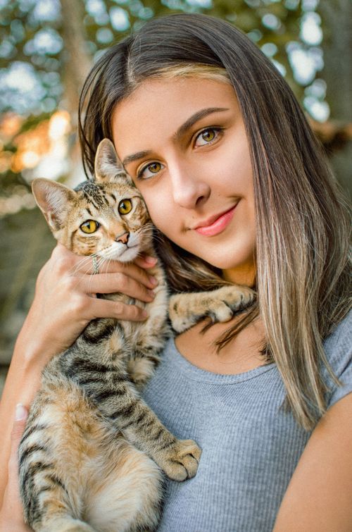 Free Portrait of a young woman embracing her tabby cat outdoors, showcasing a warm connection. Stock Photo
