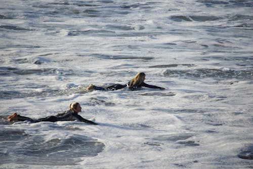 Women Swimming on Surfboards