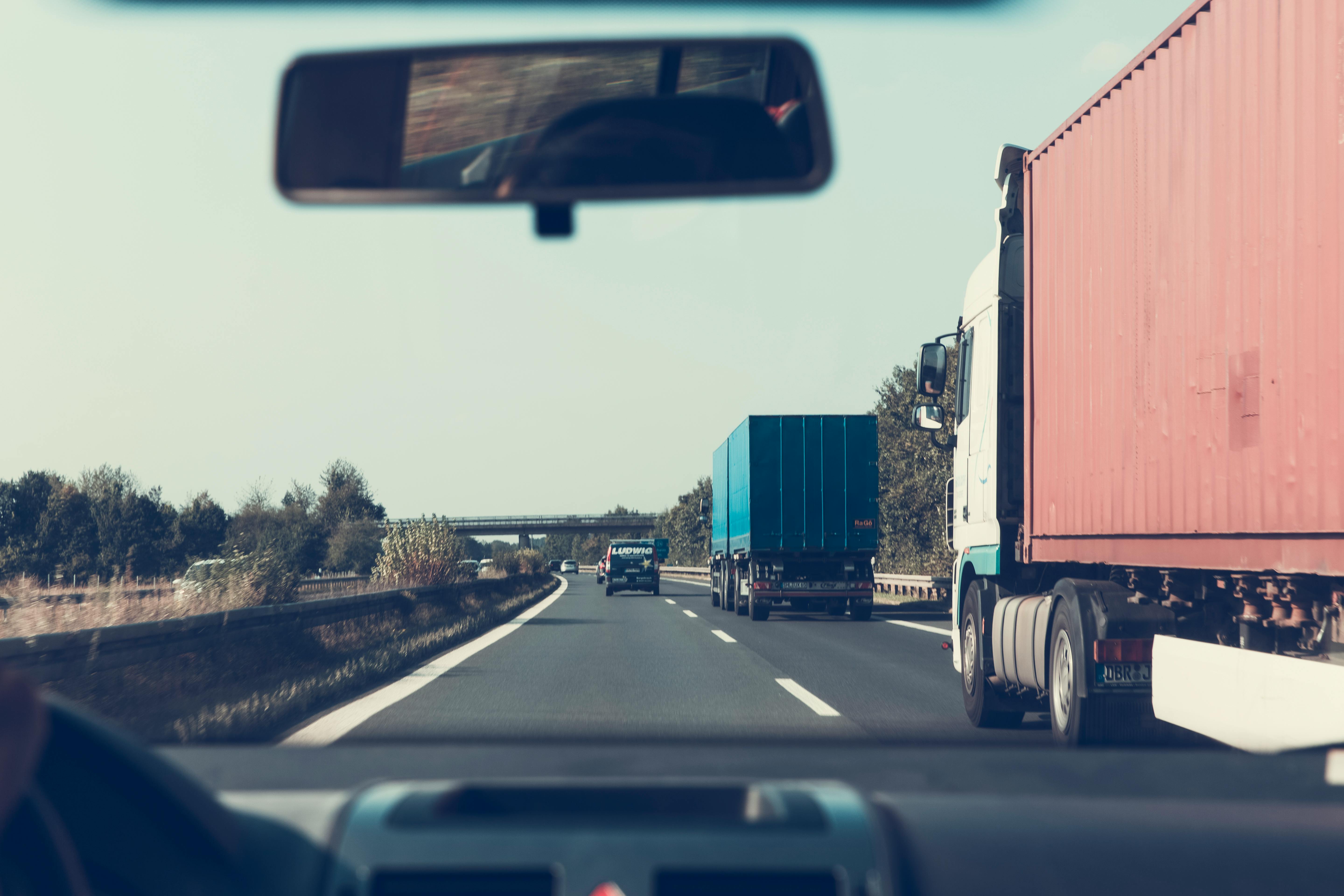 Person Driving on Road Beside Trailer Trucks