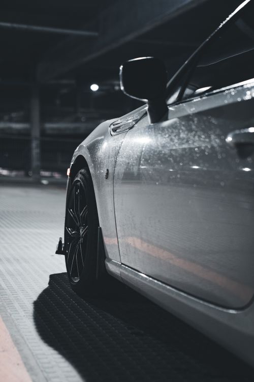 Free Close-up of a sports car side mirror and wheel in a dimly lit parking garage, with a focus on sleek design and modern aesthetics. Stock Photo