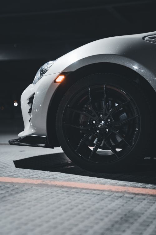 Free Close-up of a stylish white car on a city street at night, highlighting its wheel and modern design. Stock Photo