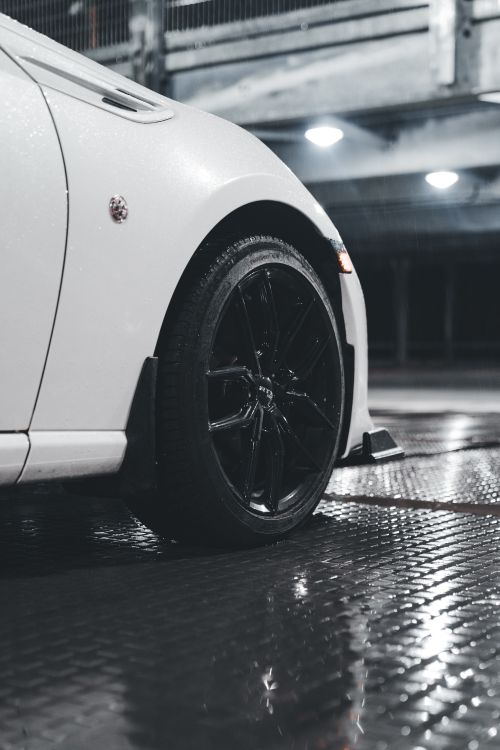 Free Stylish white car with black wheel in a wet parking garage at night, showcasing modern design. Stock Photo