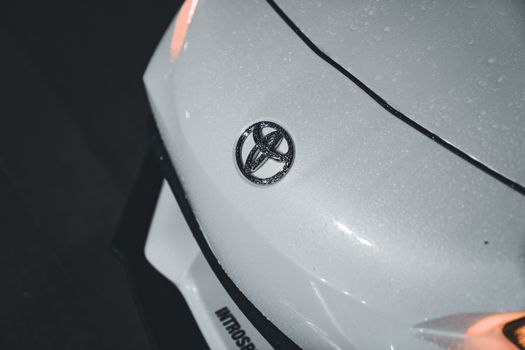 Detailed shot of a wet white car bonnet featuring the Toyota logo, highlighting texture and shine.