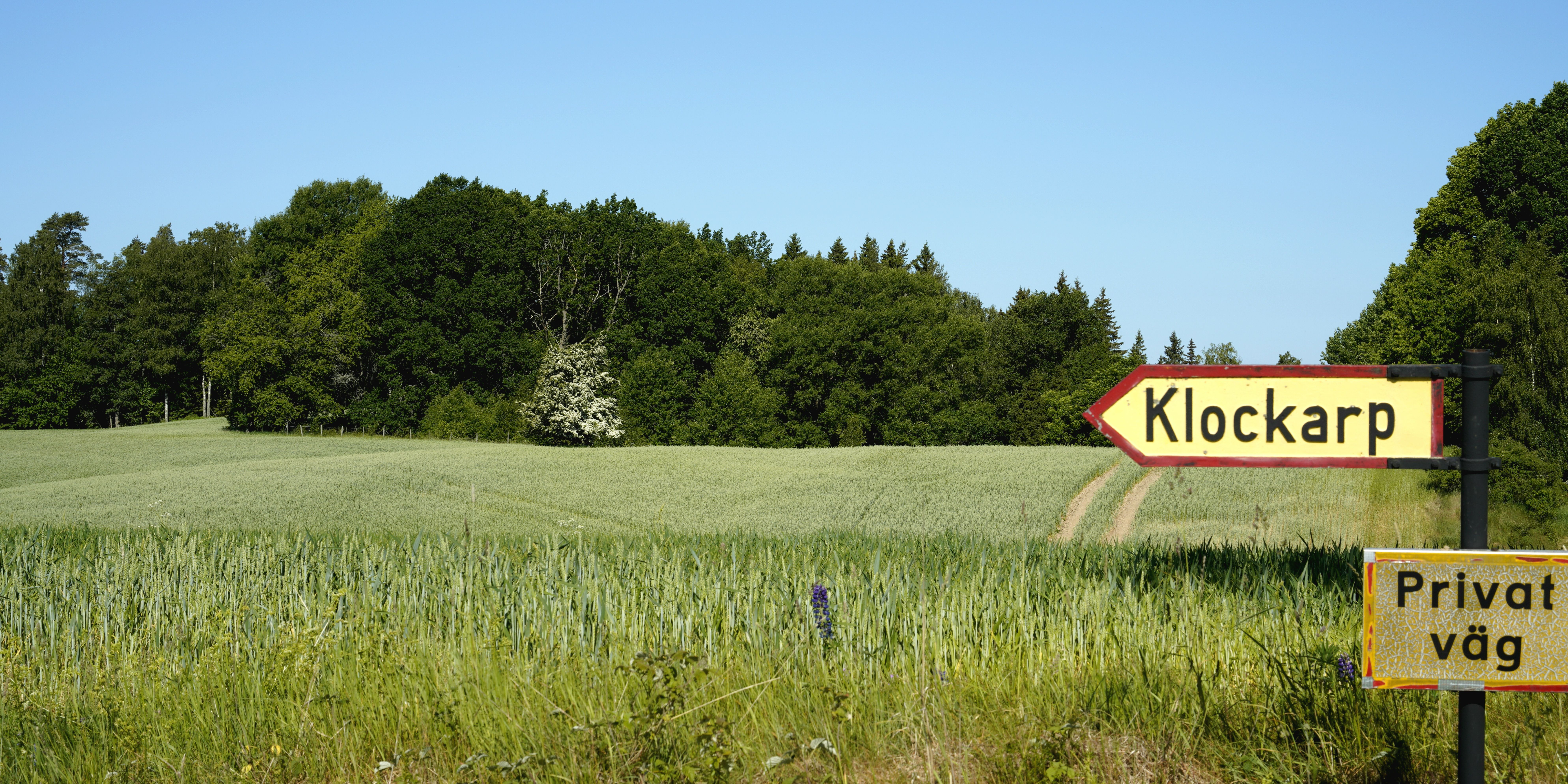 A peaceful rural landscape featuring a road sign pointing to Klockarp in lush countryside.