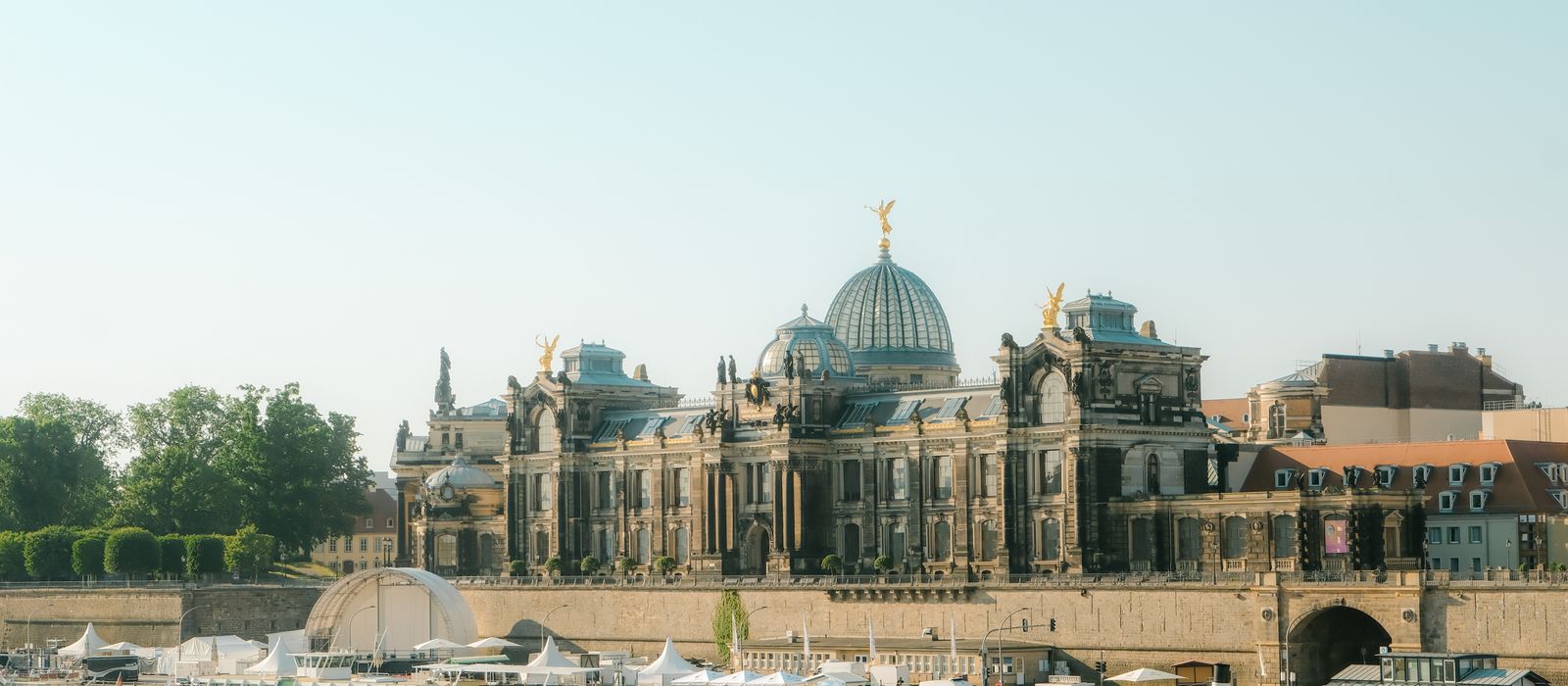 View of the Academy of Fine Arts Dresden with boats on the Elbe River under a clear sky.
