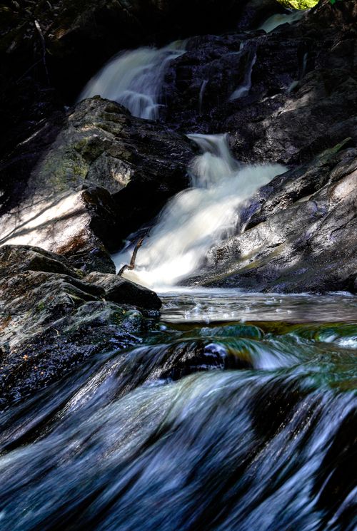 Free Stunning view of a cascading waterfall over dark rocks with flowing stream below. Stock Photo