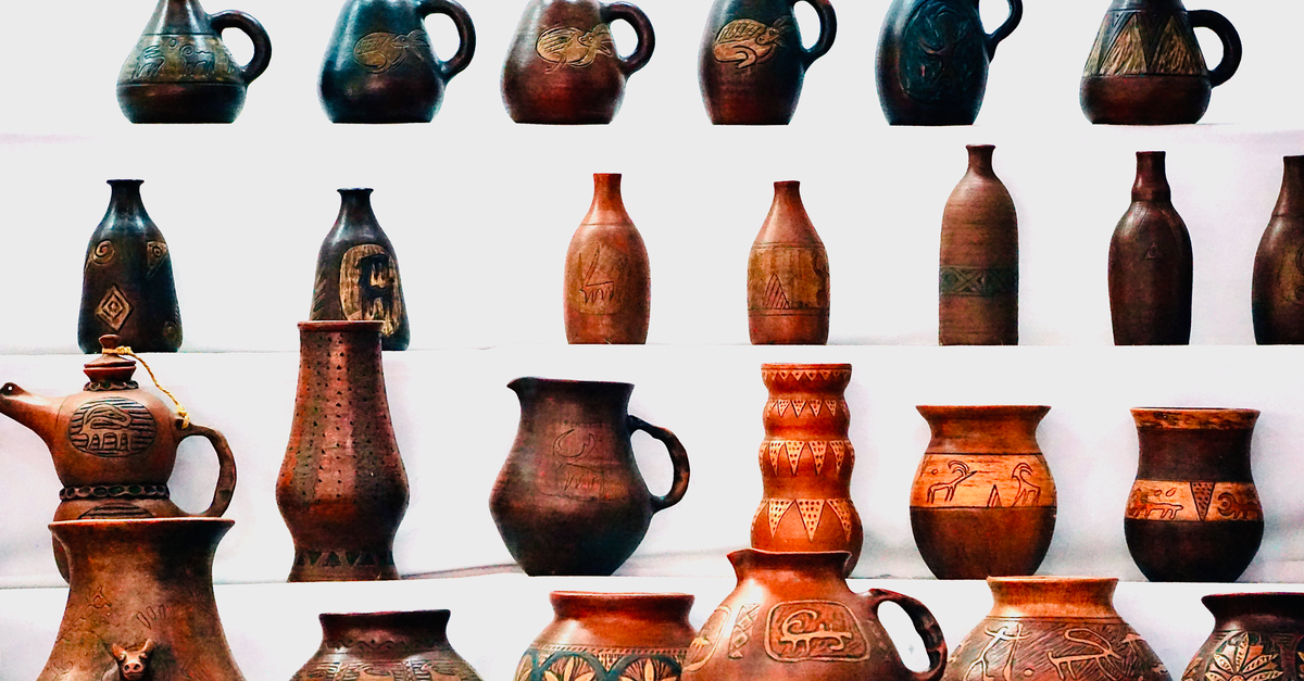 Collection of intricately designed pottery jugs and vases on a white background showcasing traditional craftsmanship.