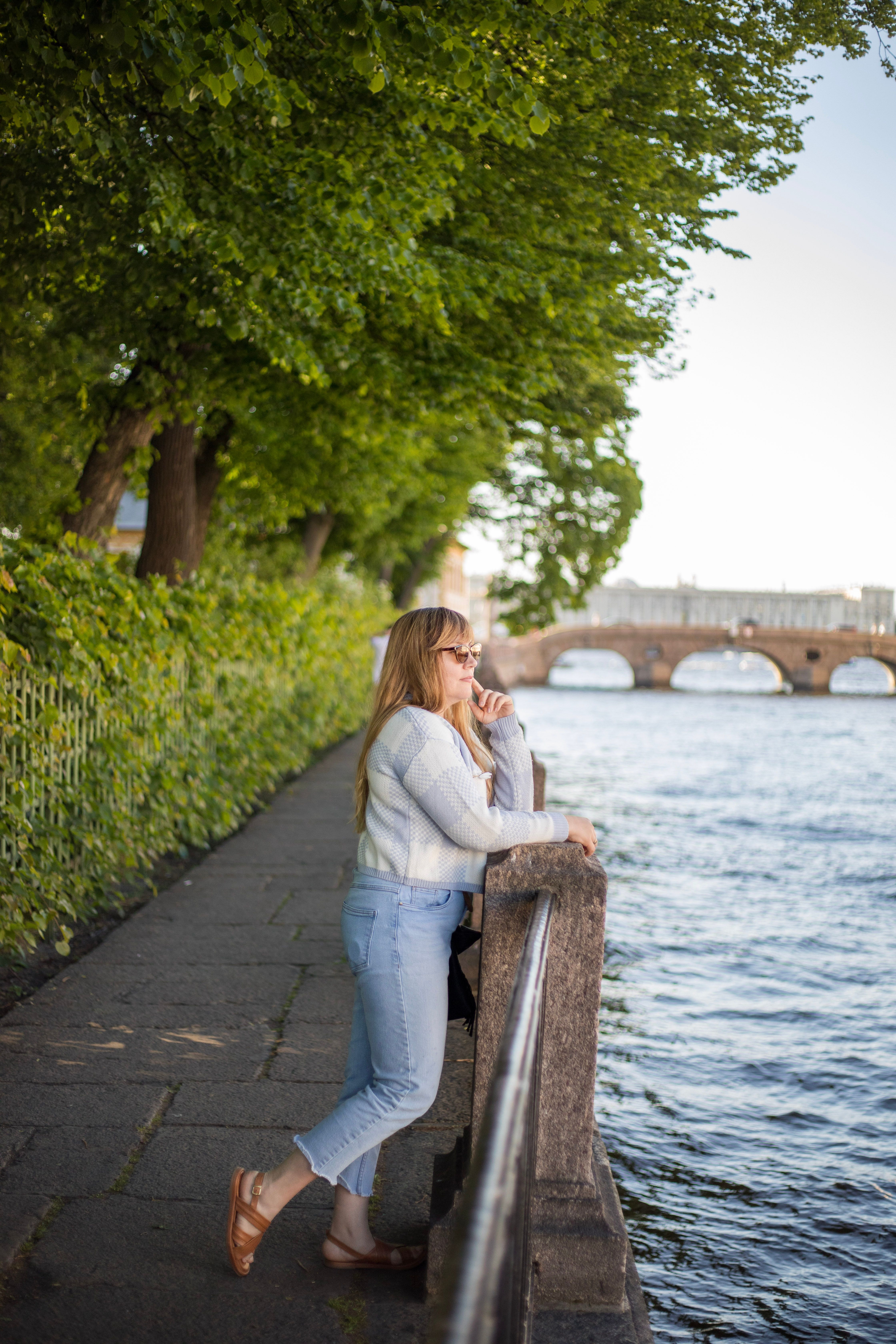 A woman is leaning against a railing near a river · Free Stock Photo