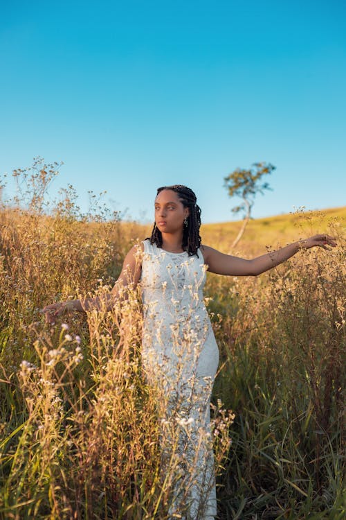 Young Woman in a White Dress Standing on a Rural Field 