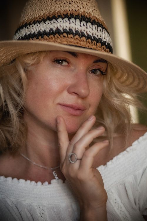 Free Portrait of a blonde woman wearing a straw hat, posing with a thoughtful expression. Stock Photo