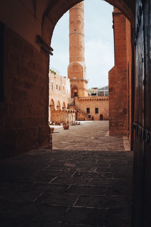 Free View of a historic mosque minaret through archways in Mardin, Türkiye. Stock Photo