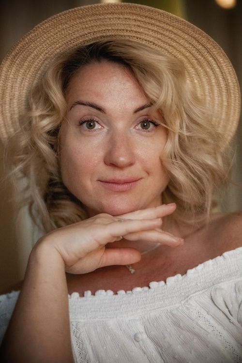 Free Portrait of a woman with curly blonde hair in a straw hat, showcasing natural beauty and elegance. Stock Photo