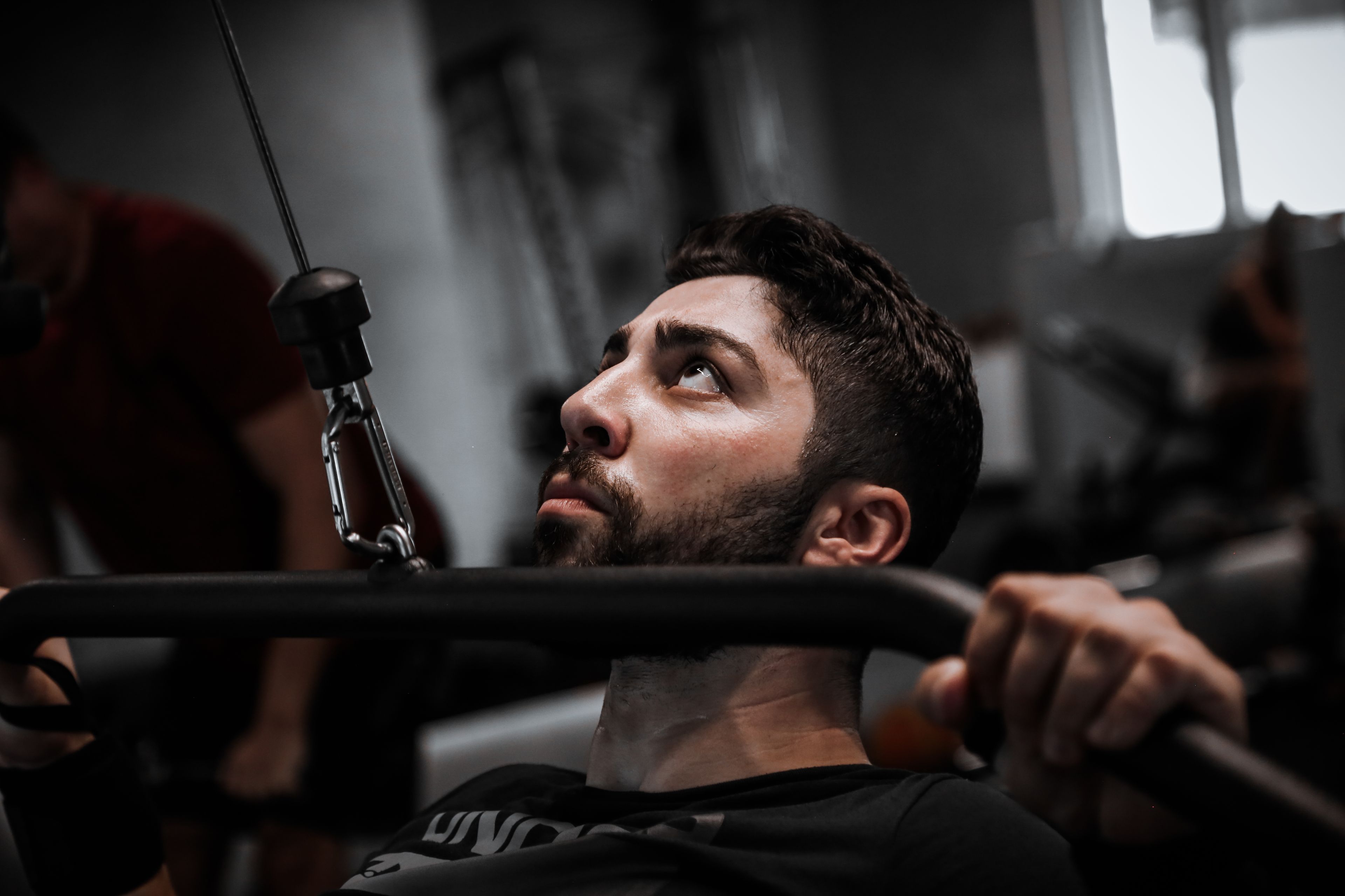 Muscular man working out with determination on gym equipment.