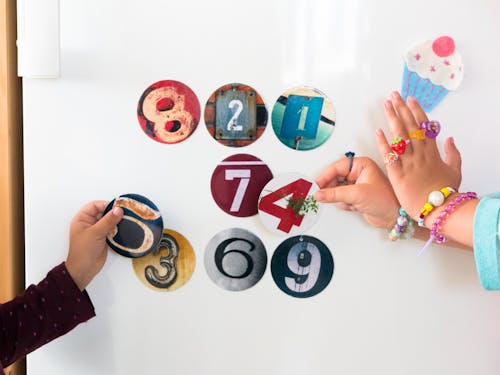 Girl and Boy Hands Holding Colorful Circles with Numbers