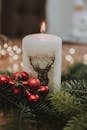 白色蜡烛的特写镜头，配以红色装饰和松枝，营造出温暖的节日氛围