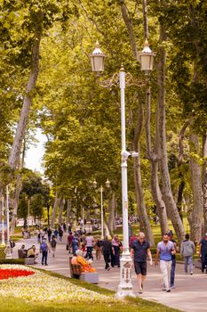 Visitors enjoy a leisurely walk among trees in Gülhane Park, İstanbul, Türkiye.