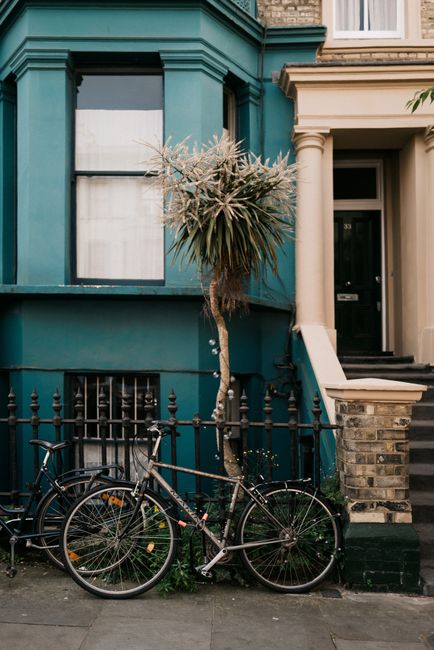 A parked bicycle in front of a vibrant townhouse in Notting Hill, London on a city street.