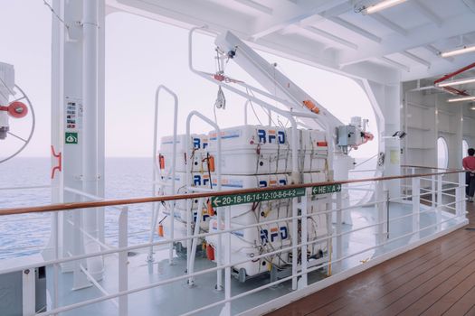 Cruise ship deck with lifeboats and safety equipment overlooking the serene ocean.