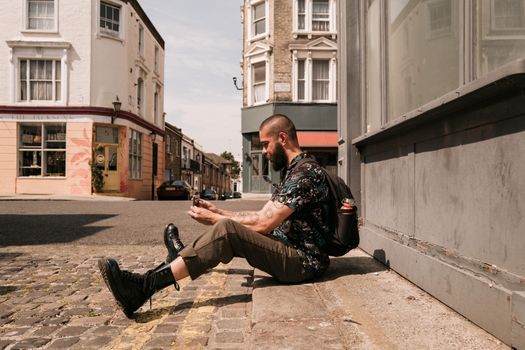 Man sitting on a street in London, taking a break from exploring the city. Summer day.