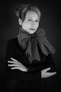 Black and white studio portrait of a woman with a large scarf around her neck, exuding elegance and style.