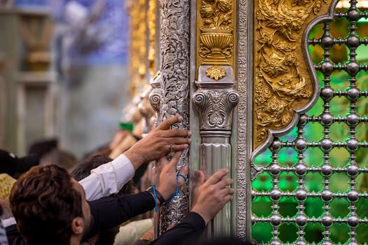 Worshippers touch a beautifully crafted shrine in Karbala, Iraq, symbolizing deep religious devotion.