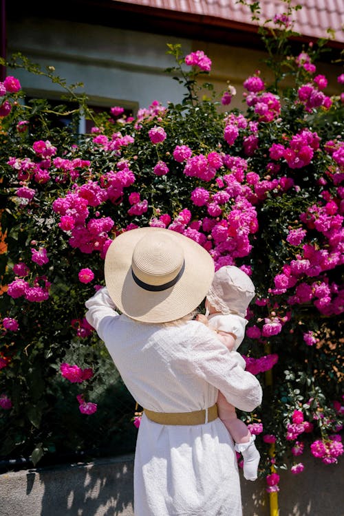 Woman with a Baby in her Arms Looking at Rose Flowers 