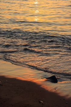 Serene sunset over the ocean waves gently lapping a sandy beach, capturing a beautiful tranquil moment.