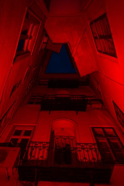 Abstract view of building with red lighting and balconies at night.