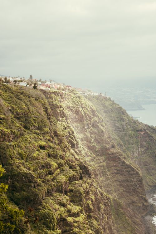 Free Drone shot depicting beautiful lush green cliffs along the Spanish coast with an expansive sea view. Stock Photo
