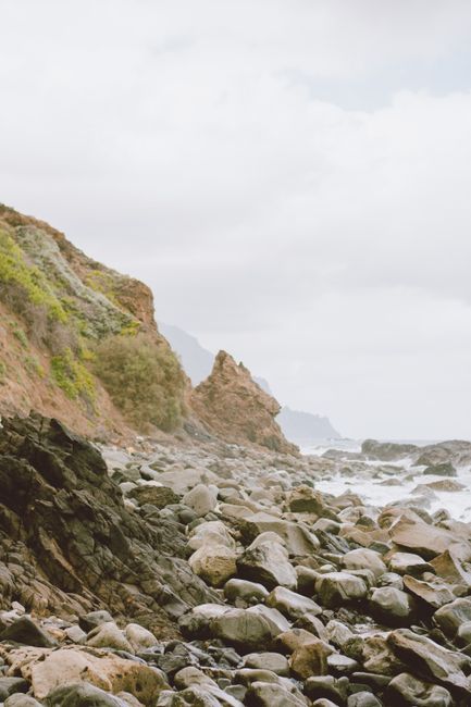 A misty and dramatic rocky shoreline with cliffs and ocean waves in Spain.