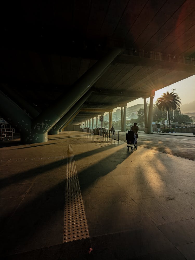 Man With Luggage On A Trolley Going To The Airport At Sunset