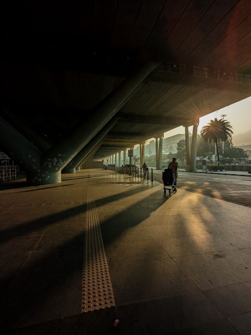 Free A traveler pushing luggage at Chennai airport during a stunning sunset, casting long shadows. Stock Photo