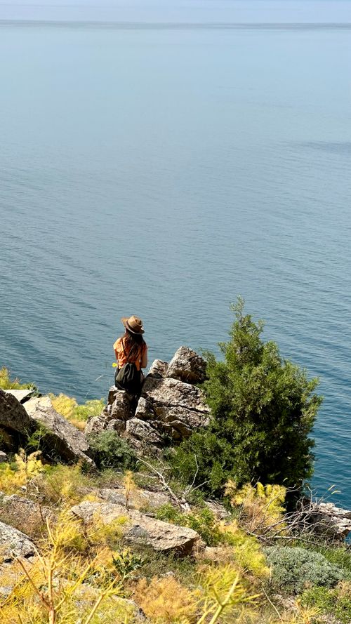 Free A woman backpacker enjoys the expansive view of Van Lake from a rocky cliff, surrounded by nature. Stock Photo