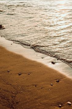 Serene sandy beach with gentle waves at sunset, capturing a peaceful shoreline scene.