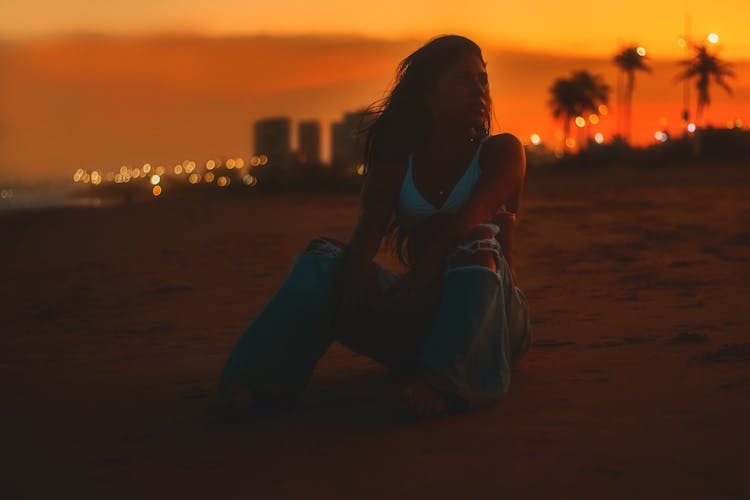 Woman Sitting And Posing On Beach In Sunset Darkness