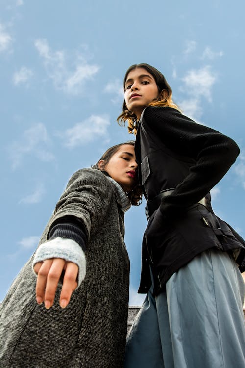 Free Low-angle Photography of Two Women Standing Under White and Blue Sky Stock Photo