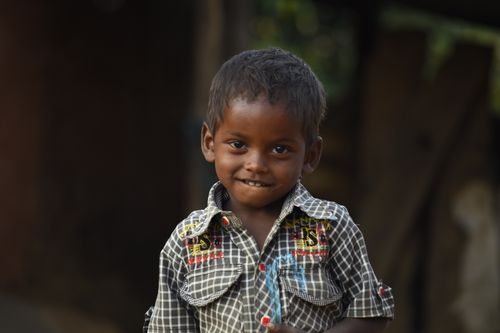 Free Young boy with a charming smile, wearing a plaid shirt outdoors in a natural setting. Stock Photo