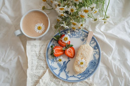 Flat Lay with Coffee Cup, Chamomile and Strawberry on a Plate