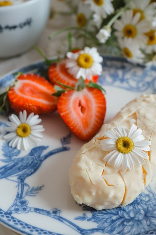 Close-up of a White Chocolate Bar and Strawberries on a Plate Decorated with Daisies 