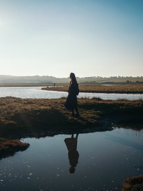 Free Woman Standing Near Body Of Water Stock Photo