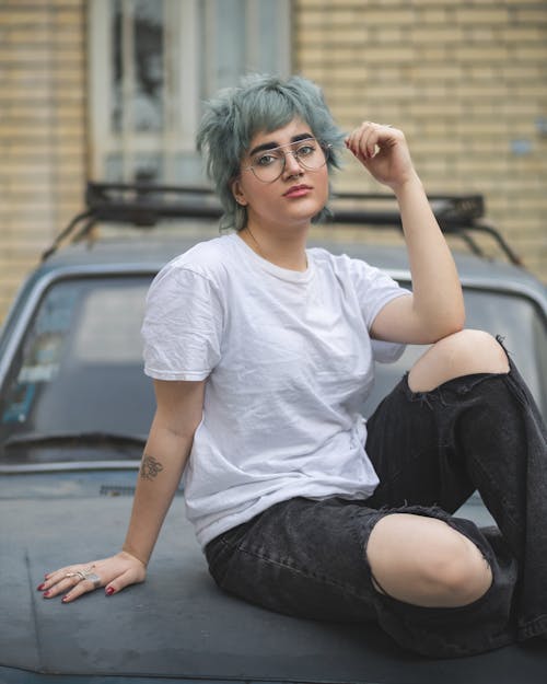 Woman with Dyed Hair and in T-shirt Sitting on Vintage Car