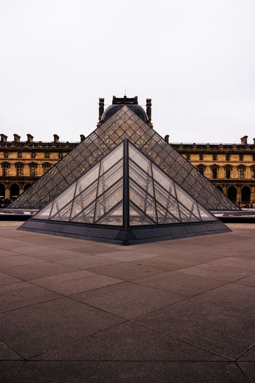 Free The Louvre Pyramid stands majestically in front of the historic museum facade in Paris. Stock Photo